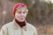 Smiling, mature woman in red hat, standing in the forest in early winter.