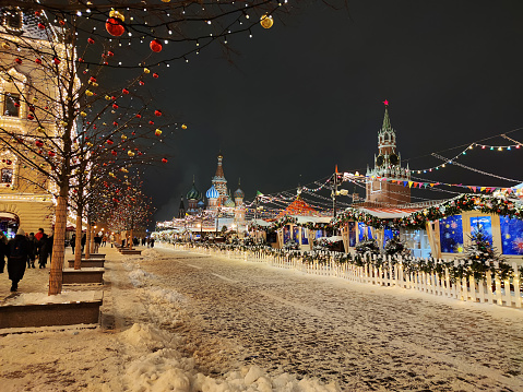 December 20, 2021. Moscow, Russia. Christmas Market fairytale Christmas tree, shining lights of shopping mall on Red Square. Festively decorated Red Square shopping malls. people walk in the evening.