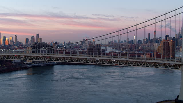 Sunrise over the Midtown Manhattan skyline over Robert F. Kennedy bridge with the view of Long Island City, Queensboro Bridge, and Roosevelt Island. Aerial drone-made video with backward-panning camera motion.