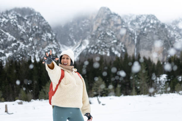 Friends on a hike through a snowy valley. They enjoy the vast landscape, the snow, play in the snow, take selfies for memories. Throwing snowballs.Mixed races.