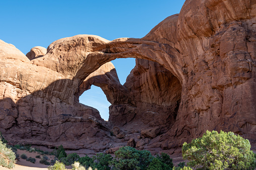 Morning sun lighting Double Arch, Arches National Park, Utah, USA.