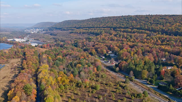 Big solar farm in the Appalachian Mountains, Pennsylvania, in a colorful fall. Aerial video with the backward-panning camera motion.