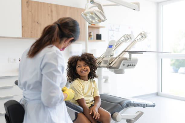 Children's dentist with children in the office. A friendly children's dentist talks about dental hygiene and tooth care in a relaxed, friendly manner with the child in the dental chair. baby teeth stock pictures, royalty-free photos & images