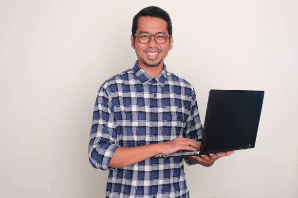 istock Adult Asian man smiling confident while holding a laptop 1710522884