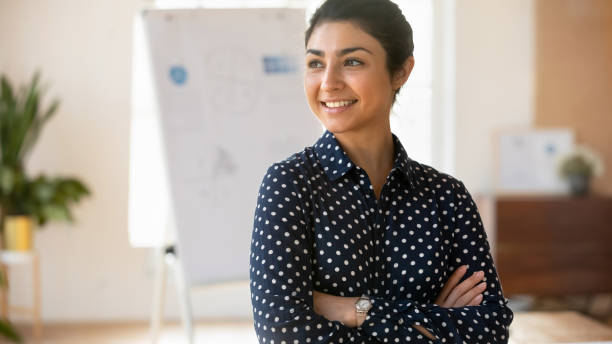 Smiling indian female employee look in distance planning stock photo
