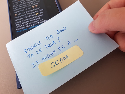 Scam alert concept. Finger pointing a note with the words Sounds Too Good To Be True It Might Be A Scam