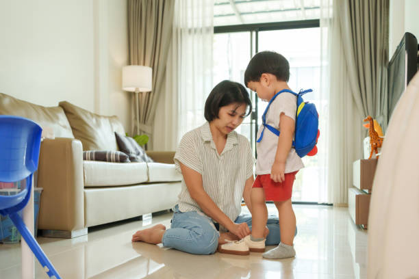 istock Asian mother helping her son putting shoes on 1710609387