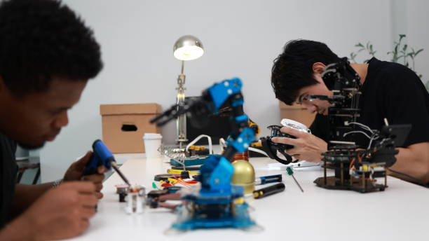 istock Two male engineers who specialize in mechatronics intently assemble and program a robot hand. 1710638662