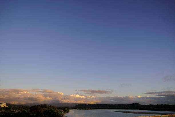 Image of evening light over the The Hokitika River. It is in the West Coast of the South Island of New Zealand. It is about 64 kilometers (40 mi) long, beginning in the Southern Alps, emerging from the narrow Hokitika Gorge after merging with the Whitcombe River, and flowing into the Tasman Sea just south of the town of Hokitika.