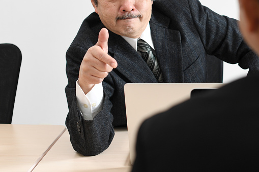 A middle-aged Asian businessman (manager) getting angry at his employees