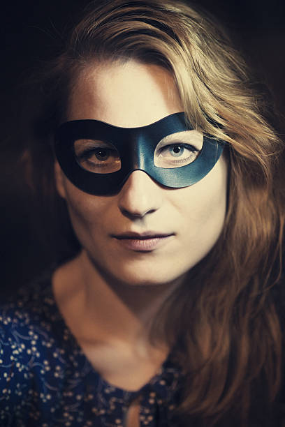 A vertical shot of a mysterious female in a mask holding up a gun