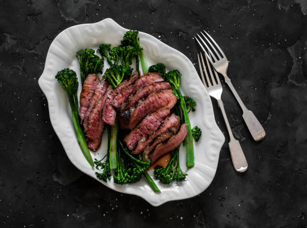 Grilled beef steak and broccolini - delicious lunch, appetizer, tapas on a dark background, top view