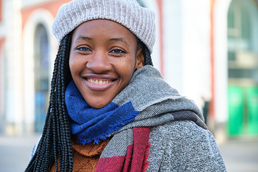 Portrait of young african woman with heterochromia looking at camera and smiling in winter.