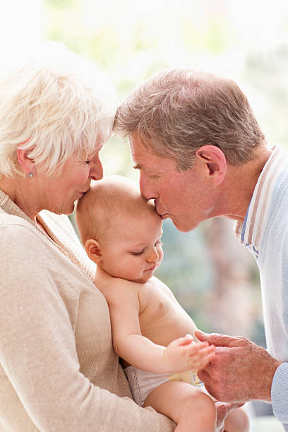 avós segurar e beijar o bebê - generation gap multi generation family vertical holding hands - fotografias e filmes do acervo