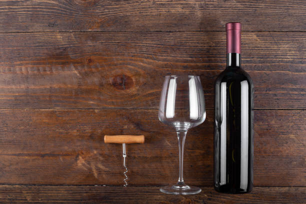 istock Bottle of red wine, a corkscrew and an empty glass on a wooden background. Space for text. 1710933896