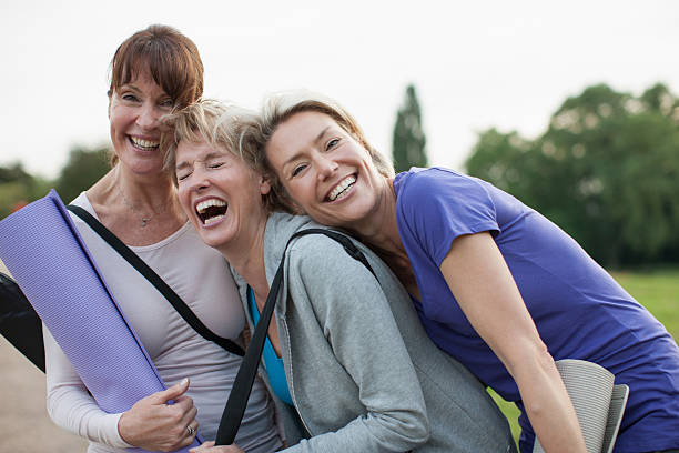 smiling women holding yoga mats - mature woman stockfoto's en -beelden