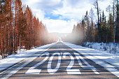 The word 2024 is written on the highway in the middle of an empty asphalt road at dawn and a beautiful blue sky. New Year 2023 concept. Concept