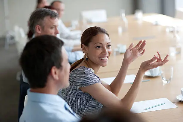 Photo of Smiling businesswoman gesturing in meeting in conference room