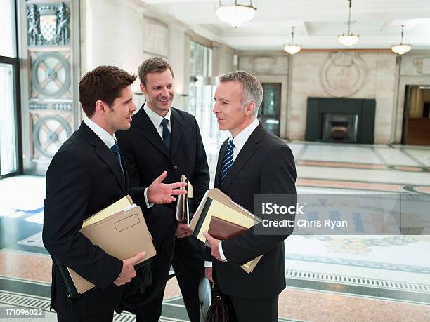 Lawyers With Files Talking In Lobby Stock Photo - Download Image Now - Lawyer, Only Men, Courthouse