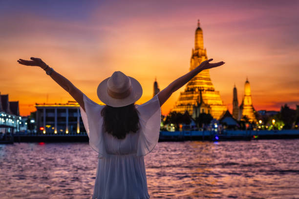 eine touristin genießt den blick auf den beleuchteten tempel wat arun in bangkok - arun stock-fotos und bilder