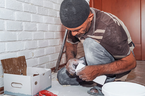 Master applies glue tiles for facing the house. The master builder decorates the walls of the apartment. Finishing the building with modern materials.