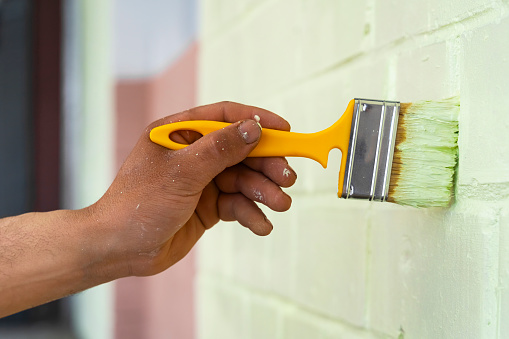 worker's hand use a brush for colored paint brick loft style on the wall