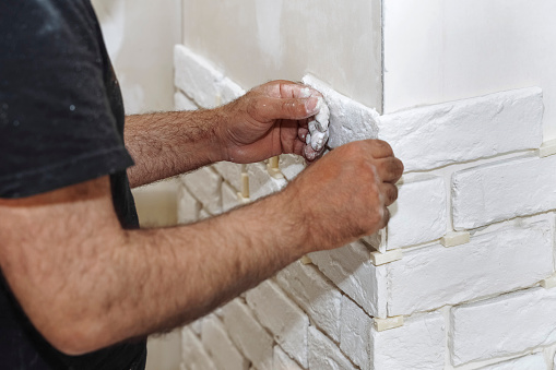 Professional Builder gluing decorative tile on wall. worker mounts decorative brick on wall