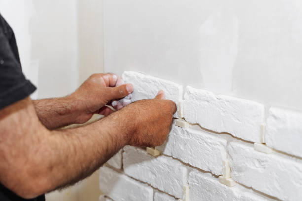 istock Stylish trendy white ceramic tile with a chamfer on the kitchen wall. Tiler hands in the process of laying white rectangular tiles on bathroom wall. Repair of apartments and bathrooms. 1710979141