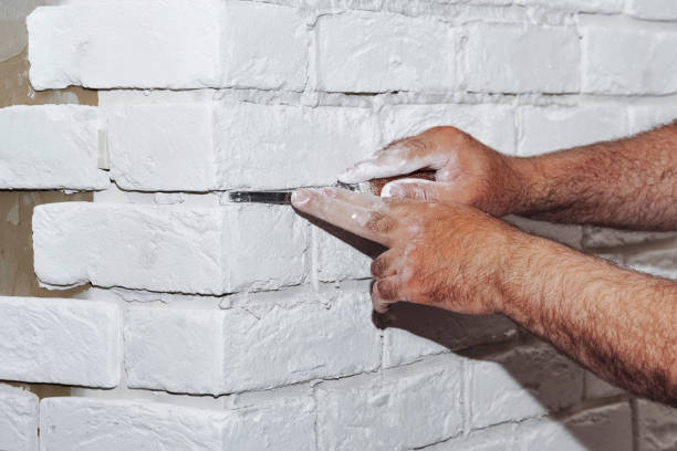 istock Stylish trendy white ceramic tile with a chamfer on the kitchen wall. Tiler hands in the process of laying white rectangular tiles on bathroom wall. Repair of apartments and bathrooms. 1710979703