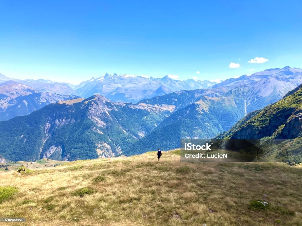 A hiking man passing through mountains A hiking man passing through mountains overlooking beautiful mountain panorama view during sunny summer day, Écrins National Park, Dauphiné Alps, France. Active lifestyle, outdoors, travel. Activity Stock Photo