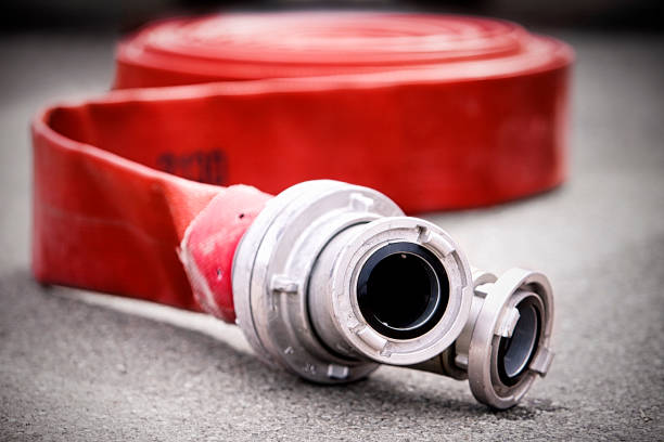 Firehose Red rolled up rubber firehose with metal nozzles fire hose photos stock pictures, royalty-free photos & images