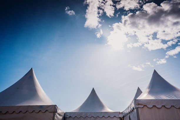 istock Peaks of three pyramidal white tents and blue sky background with space for advertisers text. 1711015237