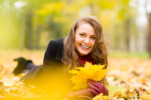 Attractive woman with autumn leaves is smiling