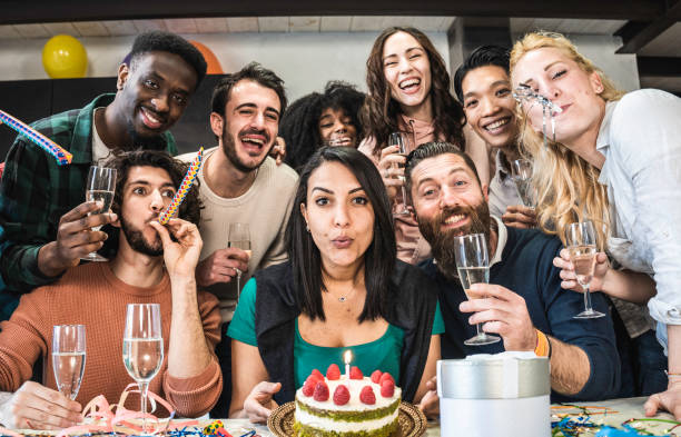 istock Multi ethnic friends having fun during birthday party - Young people looking camera during birthday party for group photo - Moroccan girl blowing out candle on cake before unwrapping her present 1711019770