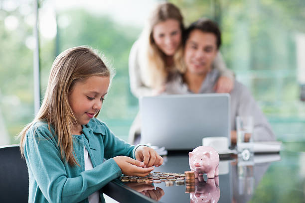 девушка считать монет с родителями в фоновом режиме - penny father стоковые фото и изображения