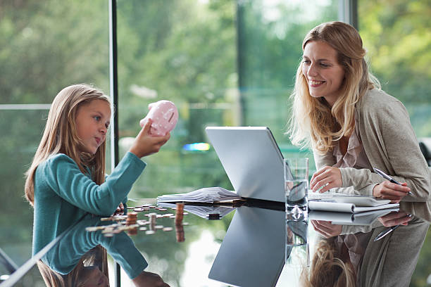 Mother watching daughter count coins from piggy bank  counting coins stock pictures, royalty-free photos & images