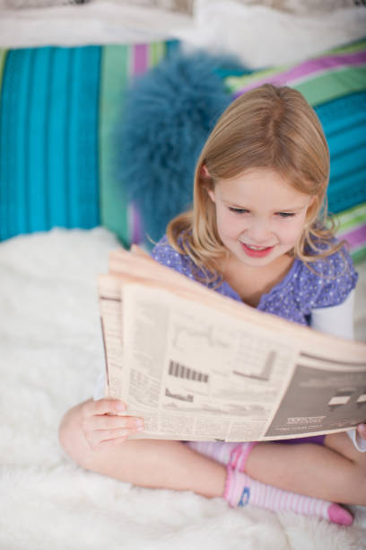 istock Girl sitting on bed reading newspaper 171102368