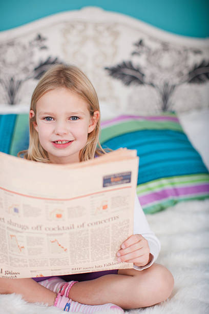 istock Girl sitting on bed reading newspaper 171102369