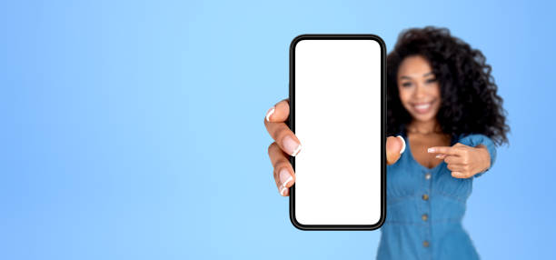 istock African woman pointing at big phone with empty screen, blue background 1711044969