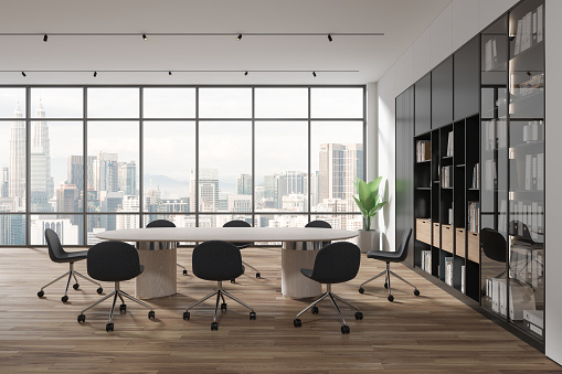 Interior of modern meeting room with white walls, wooden floor, long white conference table with gray chairs, black bookcase with folders and panoramic window with cityscape. 3d rendering