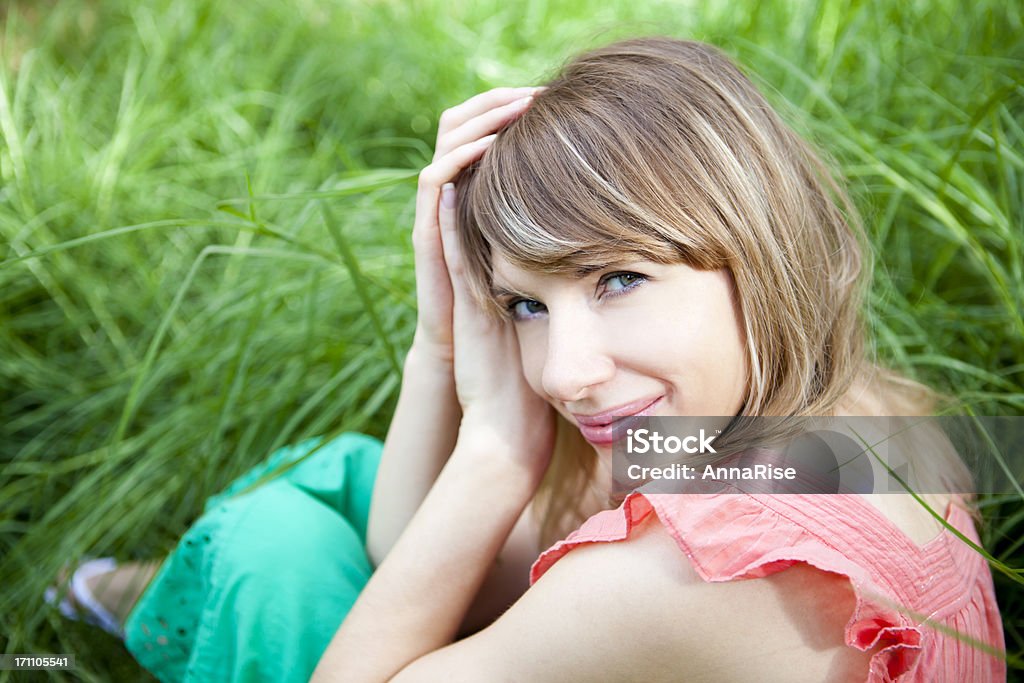 Young Beautiful Female Smiling With Hands In Hair Close-up of a happy young woman with hands in hair against natural background. 20-24 Years Stock Photo