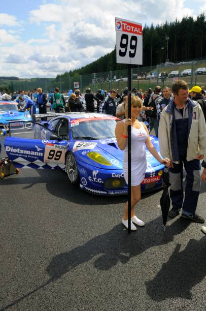 Ferrari F430 GT2 race car Spa, Belgium - July 25, 2009: JMB Racing Ferrari F430 GT2 at the start before the 2009 24 hours of Spa Francorchamps GT1 race. A grid girl is standing in front of the car. People are walking around the cars in the background. ferrari ferrari f430 italian culture action stock pictures, royalty-free photos & images