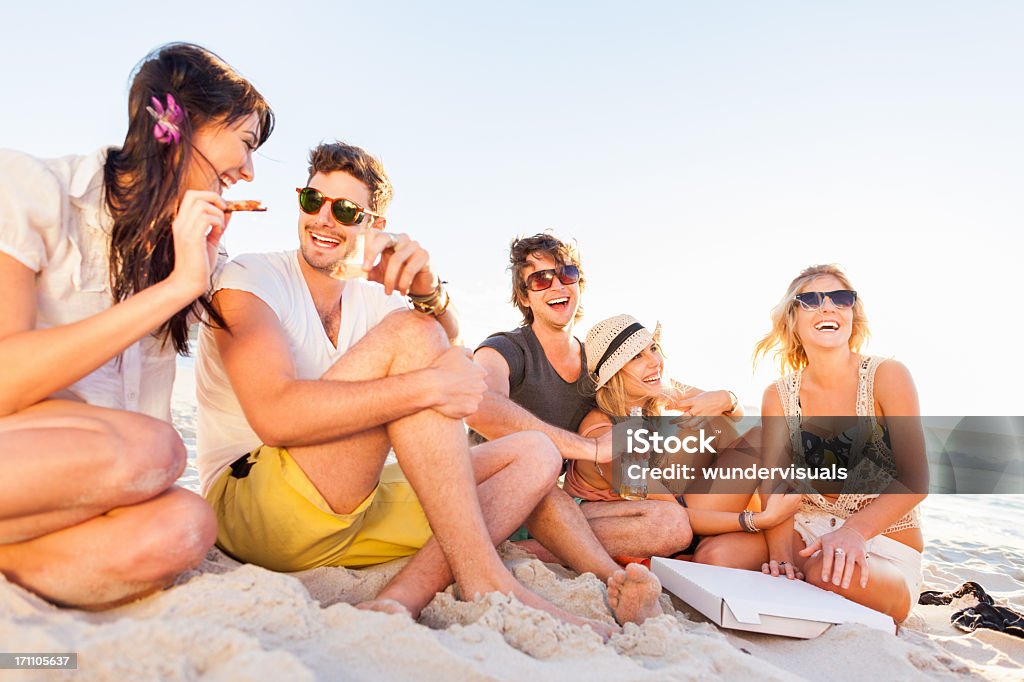 Young People Enjoying A Beach Party Young people enjoying pizza on the beach. Please checkout our lightboxes for further images. Beach Stock Photo