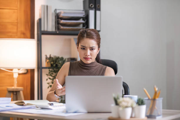 istock Young Asian businesswoman working on laptop computer, stressed has a headache and thinks hard from work at the office. 1711063895