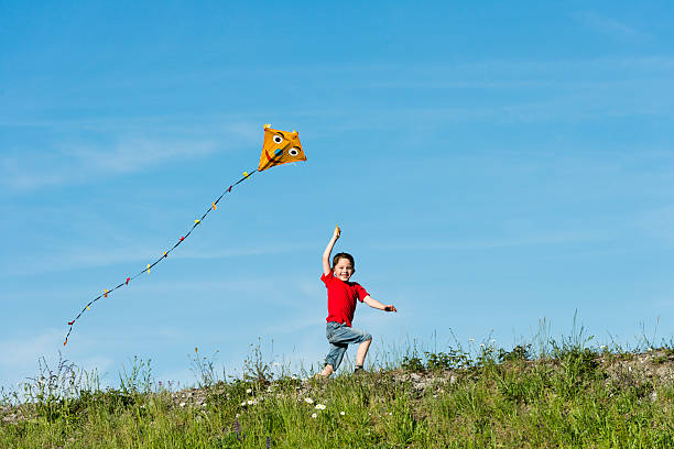 istock A boy in a red shirt running with a kite in his hand 171106487