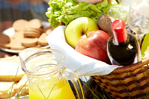Close-up of picnic basket with fruits, wine and juice