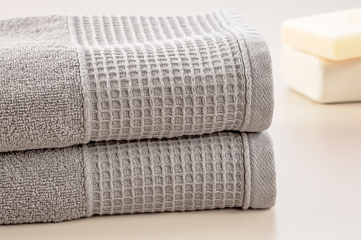 Bathroom accessories. Stack of gray soft towels and bar of soap on a gray background.