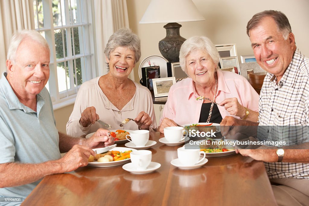 Group Of Senior Couples Enjoying Meal Together Group Of Senior Couples Enjoying Meal Together Smiling To Camera. Senior Adult Stock Photo