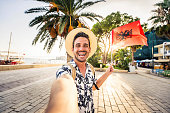 Handsome young tourist enjoying summer holiday in Sarande, Albania - Traveling life style concept with smiling man taking selfie on city street - Tourism and summertime vacation concept