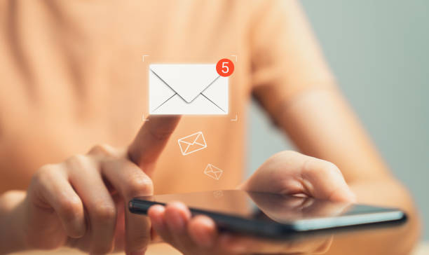 Hand holding smartphone and shows a digital screen of new email notifications.